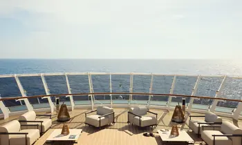Zu sehen ist die Aussicht von einem Kreuzfahrtschiff auf das offene Meer. An Deck sind Lounge-Möbel platziert.