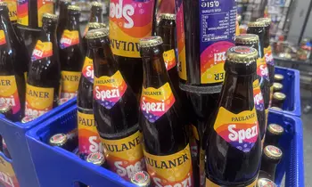 Mehrere Paulaner Spezi Flaschen in einem blauen Getränkekasten, die Etiketten mit dem orangefarbenen Paulaner Spezi Logo gut sichtbar.
