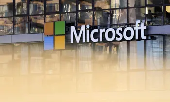 Das Logo der Microsoft Corporation ist an einer verglasten Gebäudefassade angebracht, im Hintergrund spiegeln sich Bürogebäude und Personen.