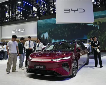 Weinrote Limousine auf einem Messestand, davor mehrere Besucher, darüber ein großes Banner mit dem BYD-Logo.