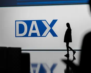 Person geht an einem Bildschirm mit dem DAX-Logo vorbei.