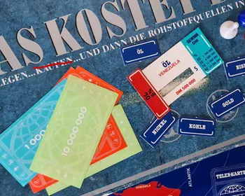 Spielmaterial des Brettspiels „Was kostet die Welt?“ mit Karten für Öl, Kohle, Eisen und Spielgeld auf einer beschädigten Spieleschachtel