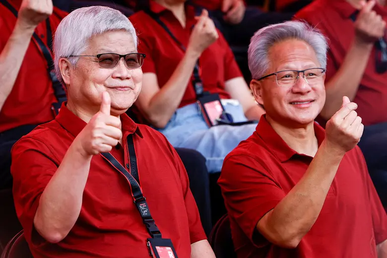 Che-chia Wei, TSMC-Chef, und NVIDIA-Gründer Jensen Huang sitzen nebeneinander in roten Polohemden und lachen in die Kamera. Wei zeigt einen Daumen hoch, Huang ein Herzzeichen.