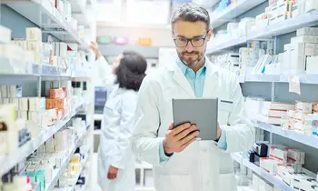 Apotheker prüft Medikamente auf Tablet – Symbolbild für den US-Healthcare-Sektor.