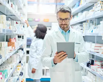 Apotheker prüft Medikamente auf Tablet – Symbolbild für den US-Healthcare-Sektor.