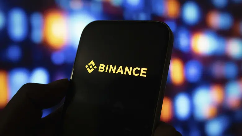 Person hält Smartphone mit Binance Kryptowährung Exchange Logo auf dem Bildschirm.