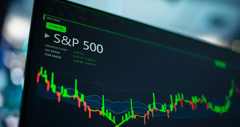 Computermonitor mit S&P-500-Kursanzeige, Candlestick-Chart in Grün und Rot sowie Kursdaten auf dunklem Hintergrund.
