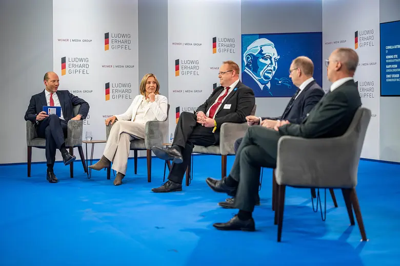 Fünf Personen sitzen bei einer Podiumsdiskussion auf einer Bühne.
