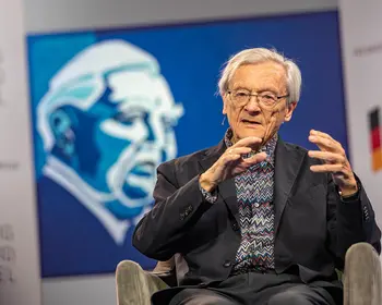 Wolfgang Schüssel sitzt mit Mikrofon auf einer Bühne.