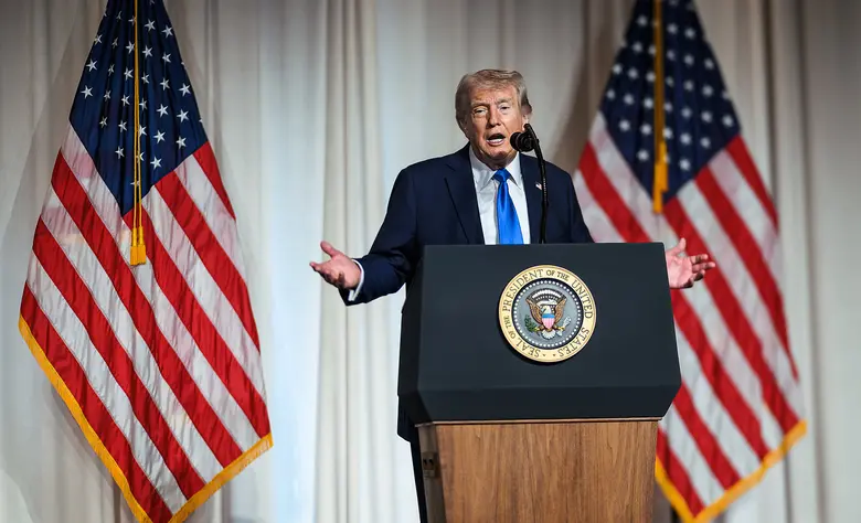 Donald Trump an einem Podium vor US-Flaggen.