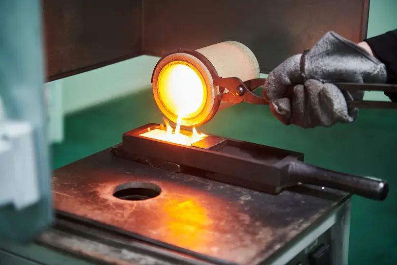 Flüssiges Gold wird aus einem Schmelztiegel in eine Barrenform gegossen.