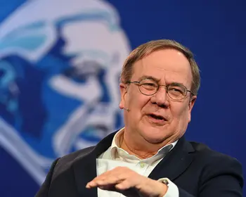 Armin Laschet mit Headset-Mikrofon vor blauem Hintergrund.