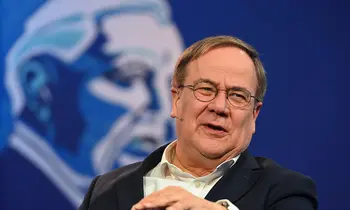 Armin Laschet mit Headset-Mikrofon vor blauem Hintergrund.