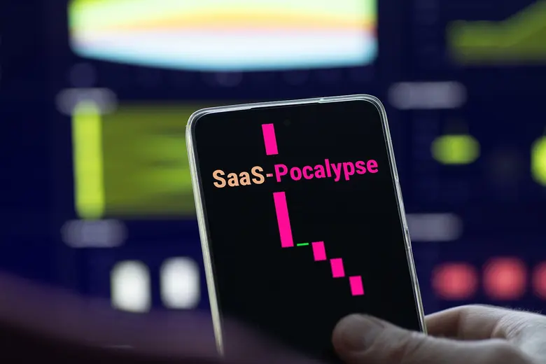Eine Hand hält ein Smartphone, auf dessen dunklem Display der Begriff SaaSpocalypse und ein fallender pinker Kurschart zu sehen sind.