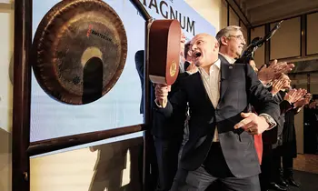 Peter ter Kulve, CEO der Magnum Ice Cream Company, schlägt vor einem großen Magnum-Schriftzug auf einer Bühne einen Gong, daneben applaudieren mehrere Personen.