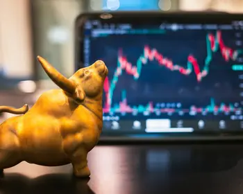 Goldene Bullenfigur steht vor einem Bildschirm mit einem Aktienchart.