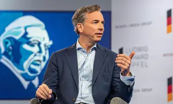 Matthias Voelkel sitzt auf einer Bühne vor einer Leinwand.