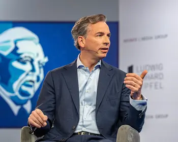 Matthias Voelkel sitzt auf einer Bühne vor einer Leinwand.