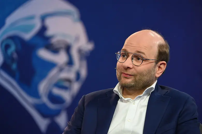 Bastian Nominacher sitzt mit Mikrofon auf einer Bühne.