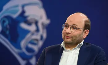 Bastian Nominacher sitzt mit Mikrofon auf einer Bühne.