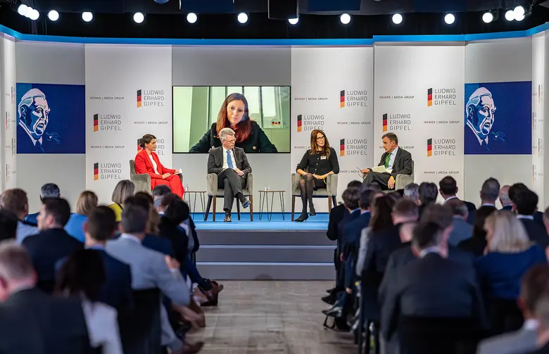 Podiumsdiskussion auf einer Bühne vor Publikum.