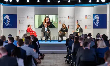 Podiumsdiskussion auf einer Bühne vor Publikum.
