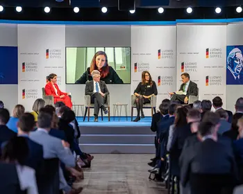 Podiumsdiskussion auf einer Bühne vor Publikum.
