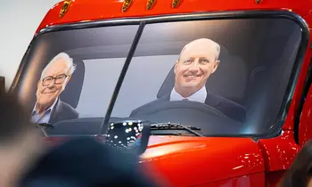 Porträts von Warren Buffett und Greg Abel sind auf einer Windschutzscheibe eines roten Trucks zu sehen.