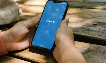 Zwei Hände halten ein Smartphone, auf dessen Display die Chase-App zu sehen ist