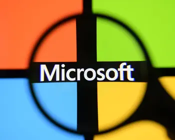Das vierfarbige Microsoft-Logo auf einem Bildschirm, durch eine schwarze Lupe fotografiert.