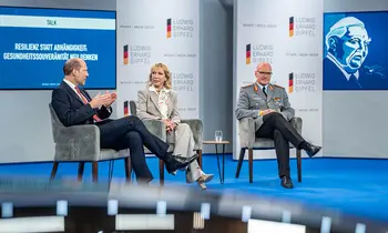 Drei Personen sitzen bei einer Podiumsdiskussion auf einer Bühne des Ludwig-Erhard-Gipfels.
