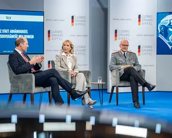 Drei Personen sitzen bei einer Podiumsdiskussion auf einer Bühne des Ludwig-Erhard-Gipfels.