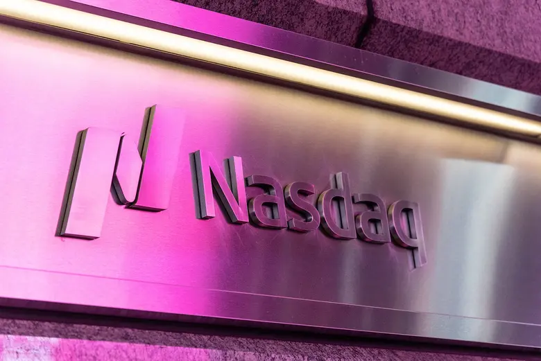 Metallschild mit dem Nasdaq-Logo und dem Schriftzug Nasdaq, das in Pink und Magenta beleuchtet wird.