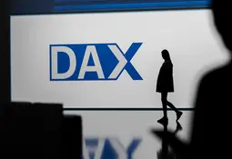 Großer blauer DAX-Schriftzug auf heller Fläche, rechts davon die Silhouette einer Person.