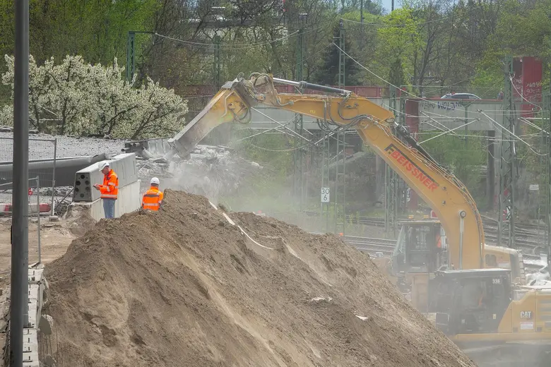 Bagger und Bauarbeiter auf einer Baustelle beim Abriss einer Brücke in Berlin.
