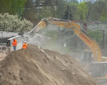 Bagger und Bauarbeiter auf einer Baustelle beim Abriss einer Brücke in Berlin.