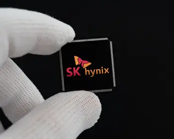 Zwei Finger in weißen Handschuhen halten einen schwarzen Chip mit dem Logo von SK hynix vor schwarzem Hintergrund.