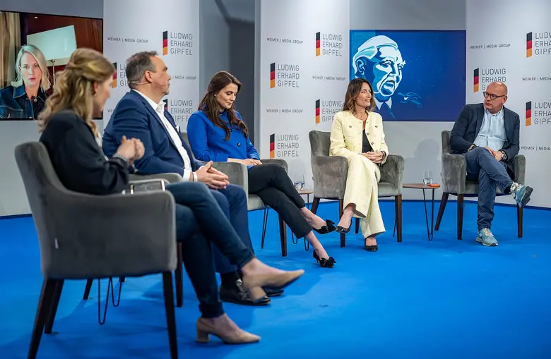 Mehrere Personen sitzen bei einer Podiumsdiskussion auf einer Bühne.