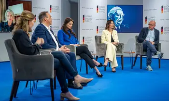Mehrere Personen sitzen bei einer Podiumsdiskussion auf einer Bühne.