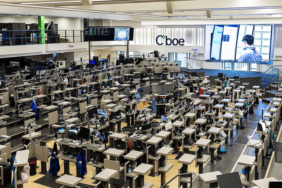 Blick in den Optionshandelssaal der Cboe in Chicago mit zahlreichen Handelsplätzen und Bildschirmen.