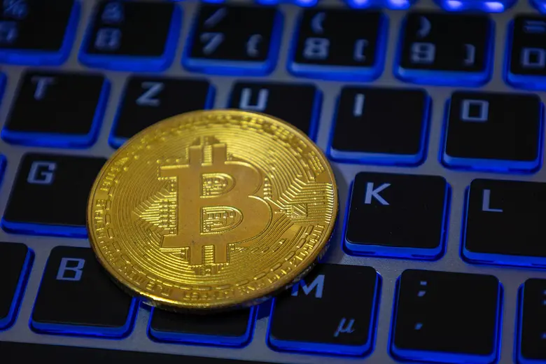 Nahaufnahme von einem symbolischen Bitcoin auf der Tastatur eines Laptops.