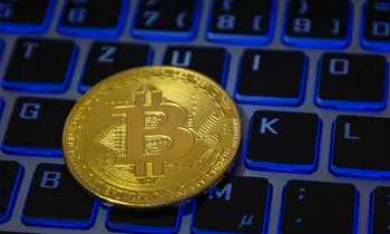Nahaufnahme von einem symbolischen Bitcoin auf der Tastatur eines Laptops.