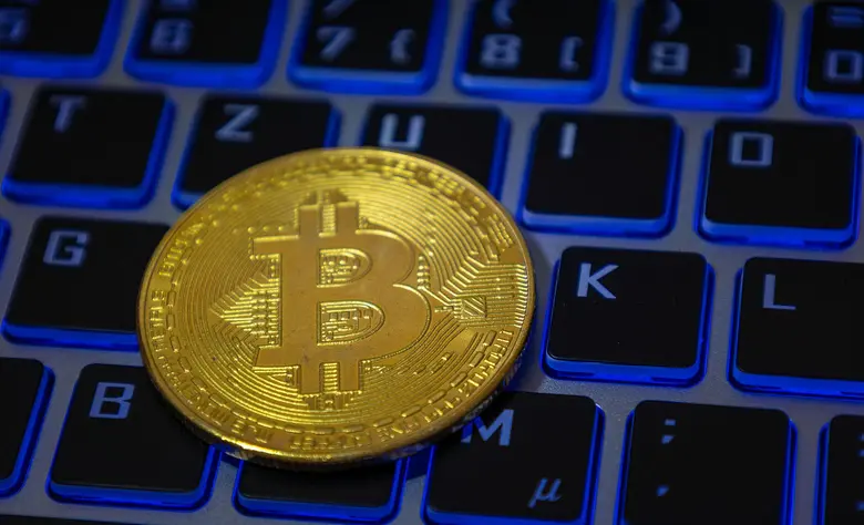 Nahaufnahme von einem symbolischen Bitcoin auf der Tastatur eines Laptops.