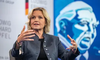Carola Ferstl spricht bei einer Podiumsdiskussion vor blauem Hintergrund.