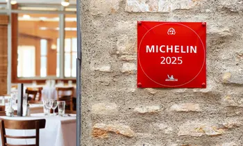 Rotes MICHELIN-2025-Schild an einer Steinwand neben einem Restaurantbereich.