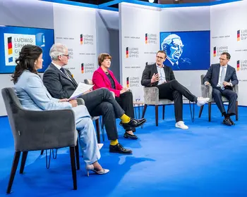 Fünf Personen sitzen bei einer Podiumsdiskussion auf einer Bühne mit Ludwig-Erhard-Gipfel-Logos.