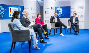 Fünf Personen sitzen bei einer Podiumsdiskussion auf einer Bühne mit Ludwig-Erhard-Gipfel-Logos.
