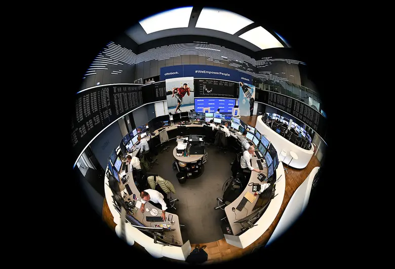 Mehrere Händler sitzen an Monitoren in einem kreisförmig wirkenden Handelssaal, aufgenommen mit einem Fisheye-Objektiv, im Hintergrund Kursanzeigen und Bildschirme.