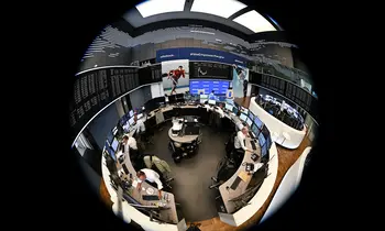 Mehrere Händler sitzen an Monitoren in einem kreisförmig wirkenden Handelssaal, aufgenommen mit einem Fisheye-Objektiv, im Hintergrund Kursanzeigen und Bildschirme.