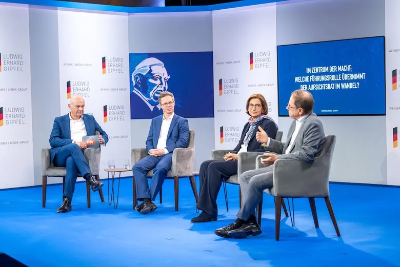 Vier Personen sitzen auf einer Bühne bei einer Podiumsdiskussion.